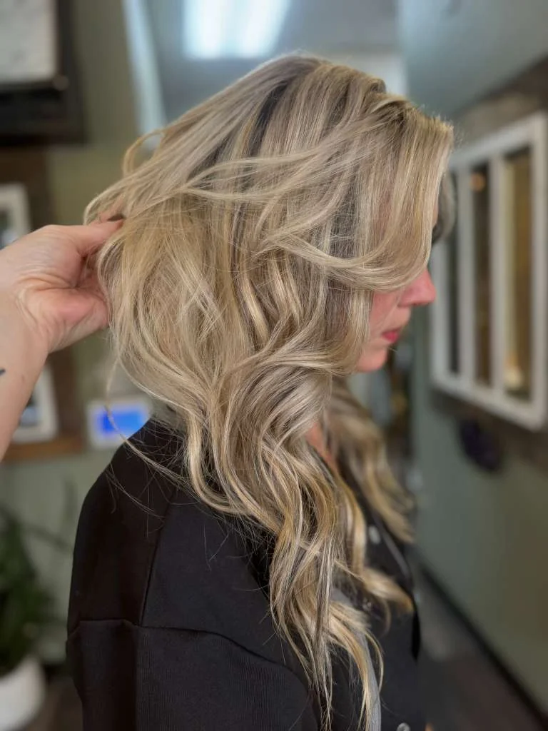 Layered beige-blonde waves with face-framing brightness, shown from the side.