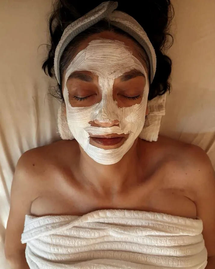 A Good Vibes facial client resting with a freshly applied cream mask