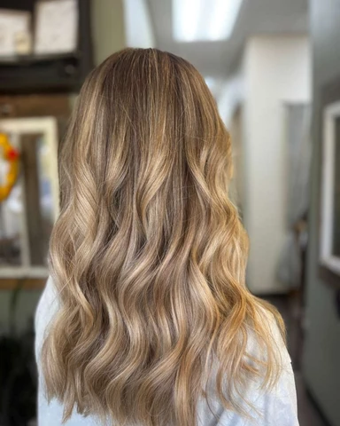Polished blonde salon waves with luminous movement through the ends