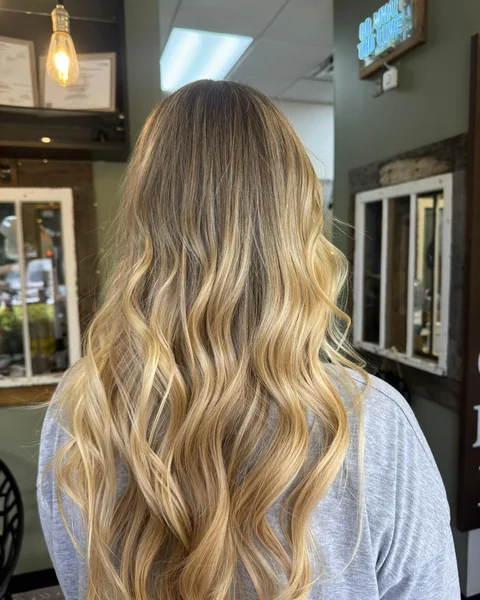 Lived-in honey blonde balayage with bright dimensional ribbons and a blended root
