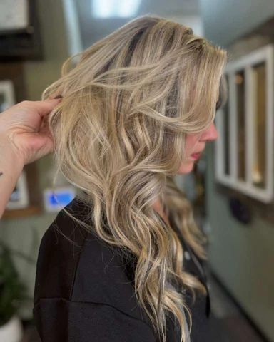 Layered blonde balayage result showing soft brightness from crown through ends