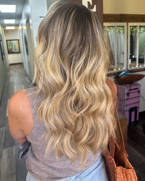 Salon client with dimensional champagne blonde waves shown from crown through ends