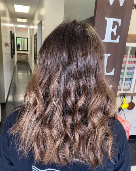 Salon client with glossy rich brunette waves and dimensional color