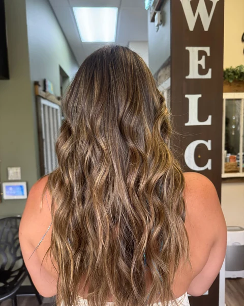 Salon client with warm dimensional brunette hair shown from crown through styled ends