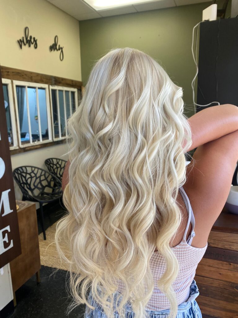Dimensional color with a softly blended root and polished waves at Good Vibes Salon